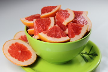 дольки спелого грейпфрута в зеленой миске