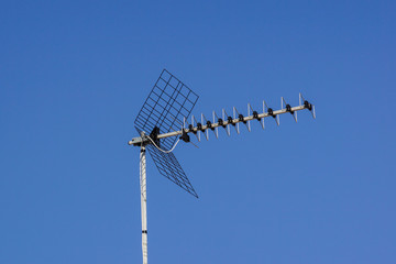 Television antenna over old metal roof on the sky background .