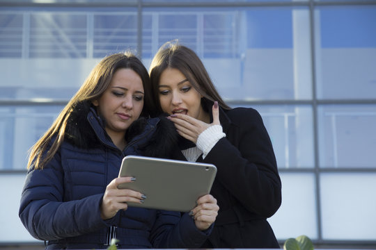 Two young business woman with a tablet