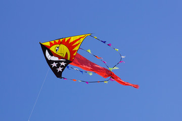 Colorful kite flying in the blue sky with wind.