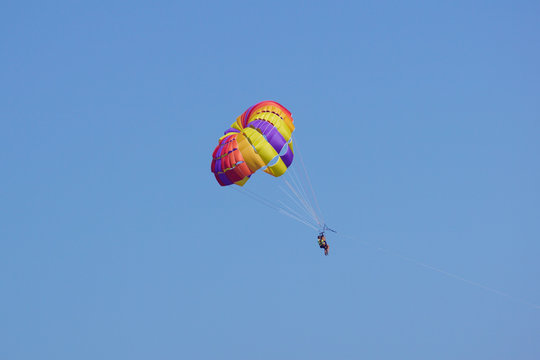 Parasailing is a popular pastime in many resorts around the world. The active form of relaxation. Focus on  parachute.