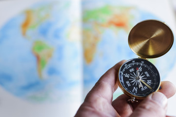 Hand haelt Kompass vor Weltkarte / Hand haelt Kompass vor Weltkarte, geringe Tiefenschaerfe.