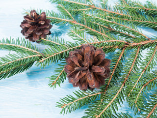 Christmas tree branches with pine cones, on wooden background