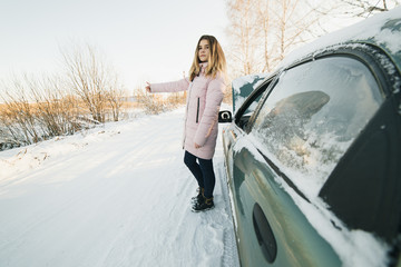 Beautiful blond girl hitchhiking by broken car