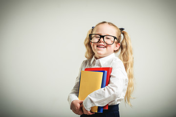 Schoolgirl in glasses reaching toward the school.