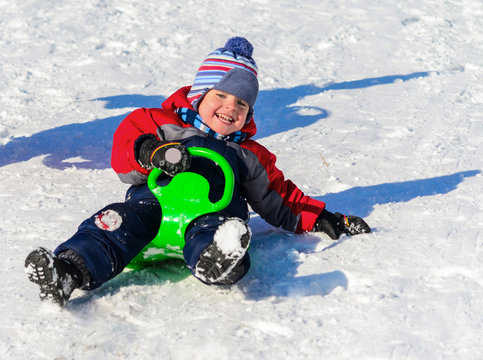 Little boy enjoying a sleigh ride. Children play outdoors in sno