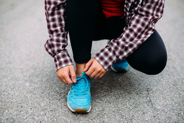 Female feet in sneakers.  Sportswoman tying her shoelaces before