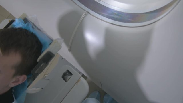 Patient in a Emergency hospital MRI scanner. Man lays in Magnetic Resonance Image device, making tomographic scanning. 4K.