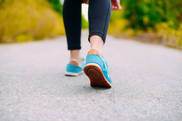 Female feet in sneakers.  Sportswoman tying her shoelaces before