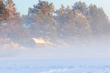Country sauna and a winter fog over the frozen river.
