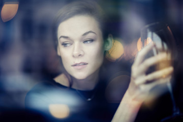 Young woman close-up portrait through window in a restaurant. leisure time with red wine