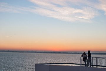 Fototapeta premium Silhouette of couple watching sunset from ferry crossing the Strait of Dover