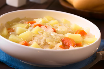 Vegetarian soup or stew made of sauerkraut, carrot and potato, photographed with natural light (Selective Focus, Focus one third into the dish)