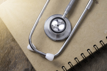 Medical concept : stethoscope on note book with sunlight on wood