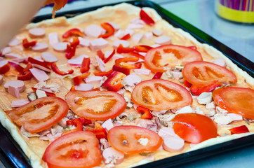 Woman hands grating cheese on the pizza. Young woman preparing the pizza in the kitchen.