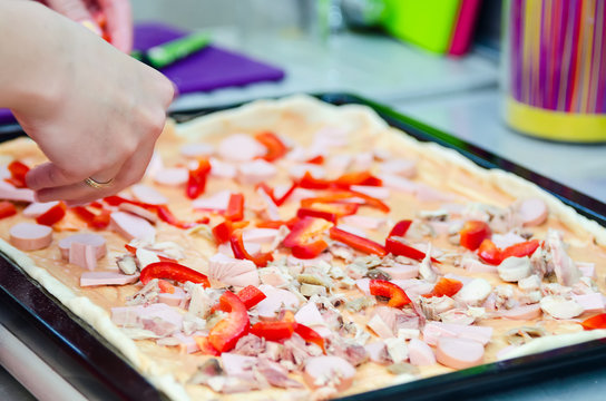 Woman hands grating cheese on the pizza. Young woman preparing the pizza in the kitchen.