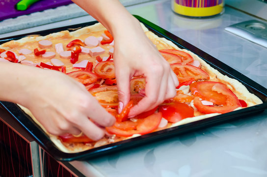 Woman hands grating cheese on the pizza. Young woman preparing the pizza in the kitchen.