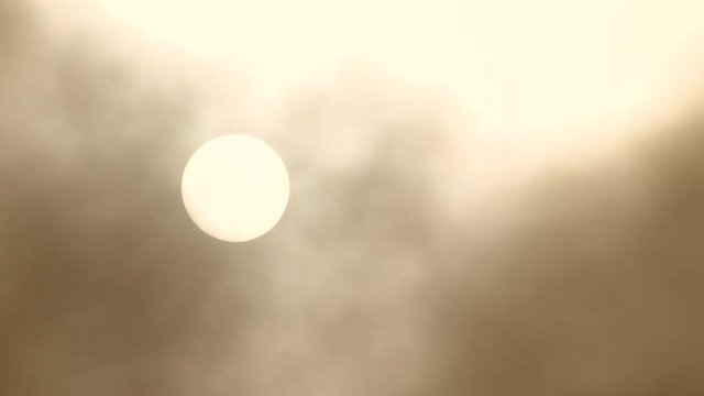 Dense smoke fills the sky with the sun shining through on hot day.