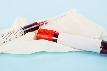 Sample blood for screening test and syringe on glove.