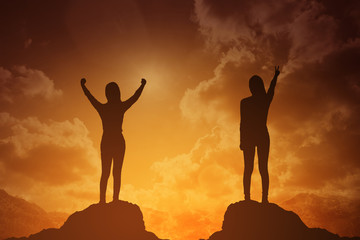 silhouette of winning success woman at sunset or sunrise standing and raising up her hand in celebration of having reached mountain top summit goal.business success concept.do it for success concept