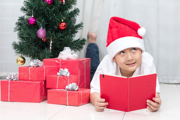 Obraz na płótnie Canvas Happy Asian Chinese little boy reading book beside Christmas pre