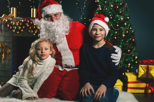 happy Santa Claus and children around the decorated Christmas tree