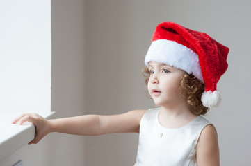 little girl in santa hat near the window