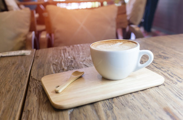 Cup of coffee with heart pattern in a white cup on wooden background