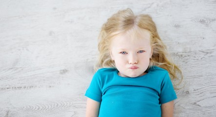 Angry girl lying on white wooden floor