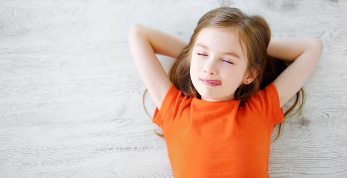 Little girl lying on white wooden floor