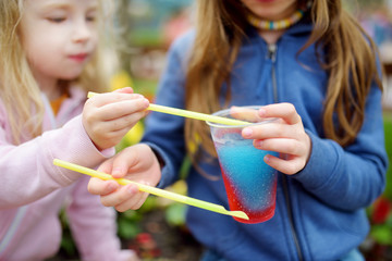 Two cute little sisters drinking frozen slushie drink