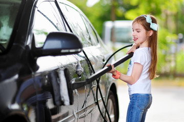 Fototapeta na wymiar Adorable little girl washing a car on a carwash