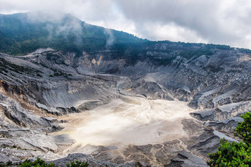 View of Tangkuban Perahu crater, showing beautiful and huge mountain crater, at the morning,illuminated by sunlight.  Using a small tree for framing. There also a blue sky and beautiful cloud