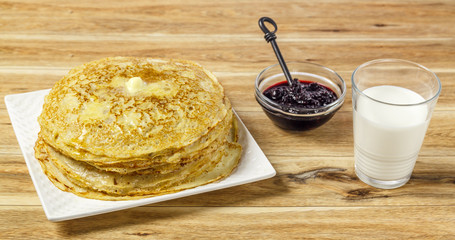 Crepes with milk and black currant jam on wood
