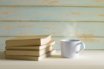 Hot coffee with books on white table in vintage color style.