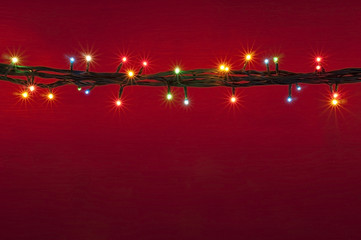 Christmas lights on red background. Multicolored light border.