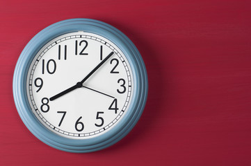 Blue wall clock on red grunge background.