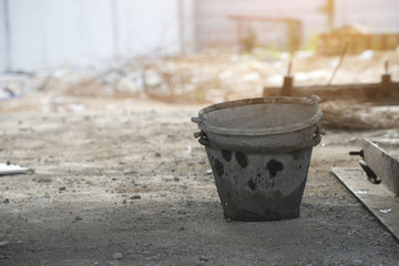 Old cement mixer bucket placed on a cement floor in the construction site.