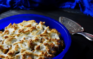 apple pie in blue baking dish spoon cake dark background 