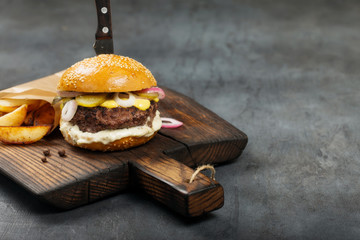 Tasty grilled beef burger with potatoes on the dark board