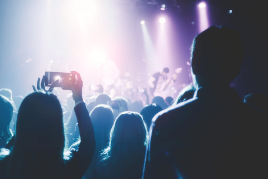 Female hands holding their smartphone and photographing concert