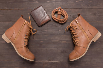 Brown wallet, brown boots and brown leather belt on the wooden b