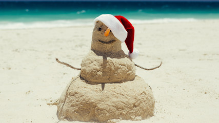 A sand sculpture of the snow (sand) man withing Merry Christmas and Happy New Year