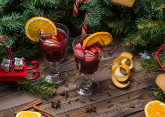 Two glasses of hot mulled wine with oranges, apples and spices