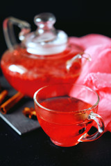 Cranberry herbal hot tea drink in glass teapot with cinnamon and