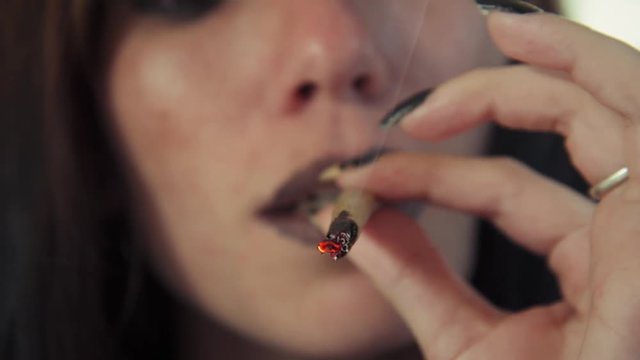 Substance abuse, drugs, narcotic and people, hispanic girl smoking hashish joint at home for smoking. Young woman using marijuana cigarette as recreational drug