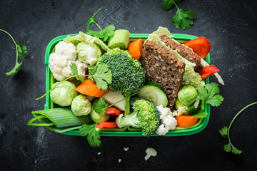 School or picnic lunch box with sandwich and vegetables