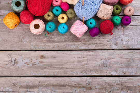 Different multi-colored skeins on retro wooden background.