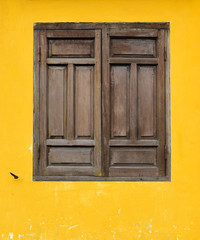 Fototapeta na wymiar Brown wooden window on yellow wall in Hoi An