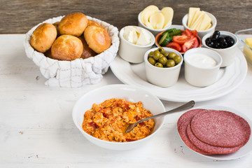 Traditional Turkish breakfast: egg, toast, pogaca pasties, vegetables, cheeses, olives and halal turkey salami, selective focus; copy space for text
